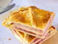 Dos porciones de empanadillas de jamón y queso, con capas doradas de masa y relleno generoso, listas para disfrutar.