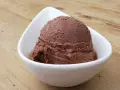 Cremoso helado de platano y chocolate en un cuenco blanco sobre una mesa de madera.