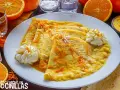 Crepes Suzette, cubiertos con ralladura de naranja y servidos con crema batida.