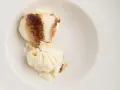 Dos bolas de helado de tiramisú con un toque de cacao en polvo en un cuenco blanco.