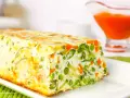 Pastel de verduras casero, con guisantes, zanahoria y calabacín, servido en un plato blanco.