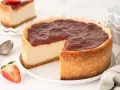 Tarta de queso vegana con cobertura de fresa, cremosa y deliciosa. Una porción ya cortada muestra su interior.