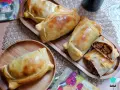 Deliciosas empanadas chilenas doradas, una rellena de carne cortada para mostrar su jugoso interior.