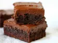 Dos deliciosos brownies con nueces apilados, cubiertos con glaseado de chocolate cremoso.