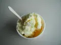 Un cremoso helado de melón en un cuenco blanco, listo para ser disfrutado con su cuchara de madera.