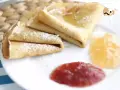 Deliciosos crepes sin gluten, espolvoreados con azúcar glas y acompañados de mermelada de fresa y melocotón.