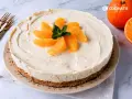Tarta de naranja cremosa, decorada con gajos de naranja y menta. Perfecta para disfrutar de un postre refrescante.
