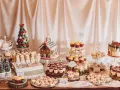 Mesa llena de postres navideños: árbol de macarons, casa de jengibre, muñecos de nieve, cupcakes y galletas.