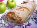 Delicioso strudel de manzana recién horneado, espolvoreado con azúcar glas y acompañado de manzanas verdes frescas y canela.