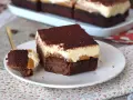 Un trozo de brownie de chocolate con una capa cremosa y espolvoreado de cacao. ¡Un delicioso brownie chocolate blanco!