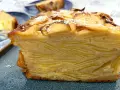 Un trozo de pastel de capas con trozos de manzana en la parte superior, espolvoreado con azúcar glas. Un postre invisible aux pommes.