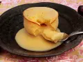 Coulant de chocolate blanco con interior cremoso, servido en plato negro con cerezas.