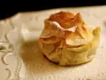 Delicioso saquito de pasta filo relleno de queso, espolvoreado con azúcar glas sobre un plato blanco.