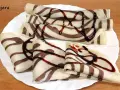 Deliciosos crepes de chocolate rayados, enrollados y doblados, cubiertos con sirope de chocolate.