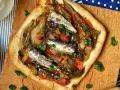 Coca de recapte con verduras asadas y sardinas, decorada con perejil fresco.