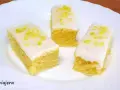 Tres porciones de brownie de limón con glaseado blanco y ralladura de limón, servidas en un plato blanco.