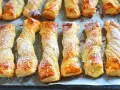 Deliciosos lazos de hojaldre dorados y espolvoreados con azúcar glas, listos para disfrutar.