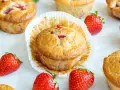 Delicioso postre con fresas, muffins dorados con trozos de fresa y fresas frescas alrededor.
