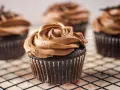 Deliciosas magdalenas sin huevo con glaseado de chocolate cremoso, decoradas como una rosa.