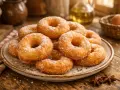 Rosquillas de anís recién hechas, cubiertas de azúcar, apiladas en un plato rústico sobre una mesa de madera.