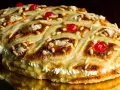 Deliciosa coca de Sant Joan rellena de crema, decorada con piñones, cerezas rojas y azúcar.