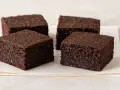 Cuatro deliciosos brownie avena y cacao, con textura rústica y color intenso, servidos sobre papel de horno.