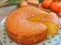 Bizcocho de mandarina y yogur, esponjoso y dorado, con una porción cortada. Mandarinas frescas al fondo.