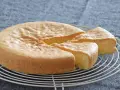 Un esponjoso bizcocho sin gluten, recién horneado y cortado en porciones, descansa sobre una rejilla.