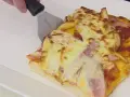 Una rebanada de pan pizza con papas fritas y jamón, lista para ser servida.