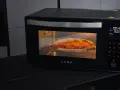 Horno AENO precalentando para pizza, con una pizza dorada en su interior.
