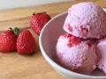 Delicioso helado de frutos rojos con fresas frescas al lado, listo para disfrutar en un día caluroso.