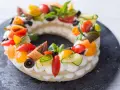 Deliciosa cream tart circular adornada con tomates, pepino, aceitunas y albahaca.