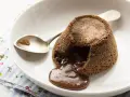 Coulant de chocolate recién horneado, con su interior líquido de chocolate derretido, listo para ser disfrutado con una cuchara.
