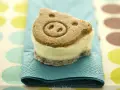 Un delicioso helado de galleta con forma de cerdito, servido sobre una servilleta azul turquesa.