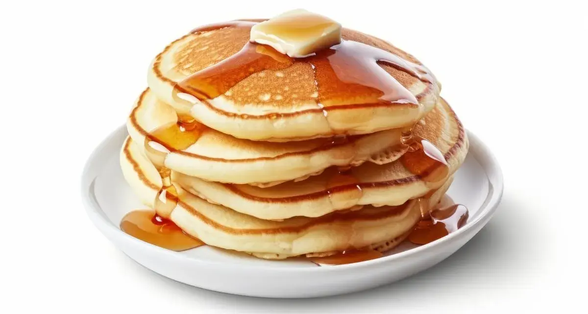 Pila de pancakes dorados con mantequilla y sirope cayendo. ¡Perfectos para tu receta de pancakes!