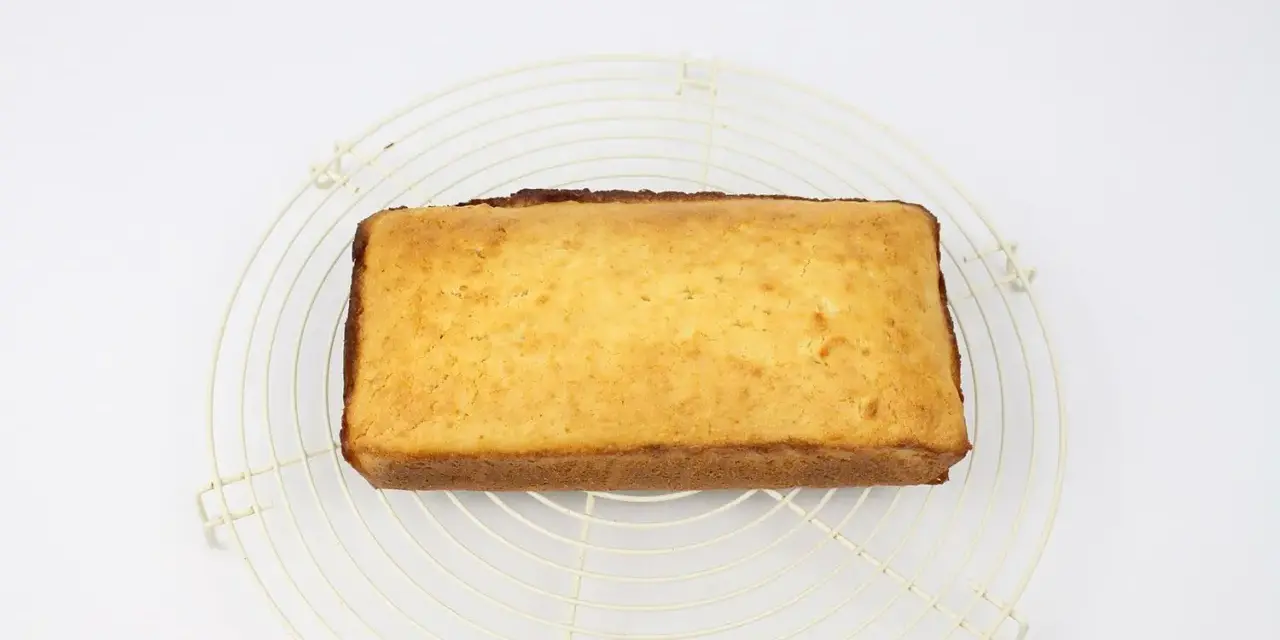 Bizcocho de coco dorado y esponjoso enfriándose sobre una rejilla.