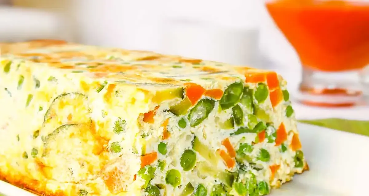 Pastel de verduras casero, con guisantes, zanahoria y calabacín, servido en un plato blanco.
