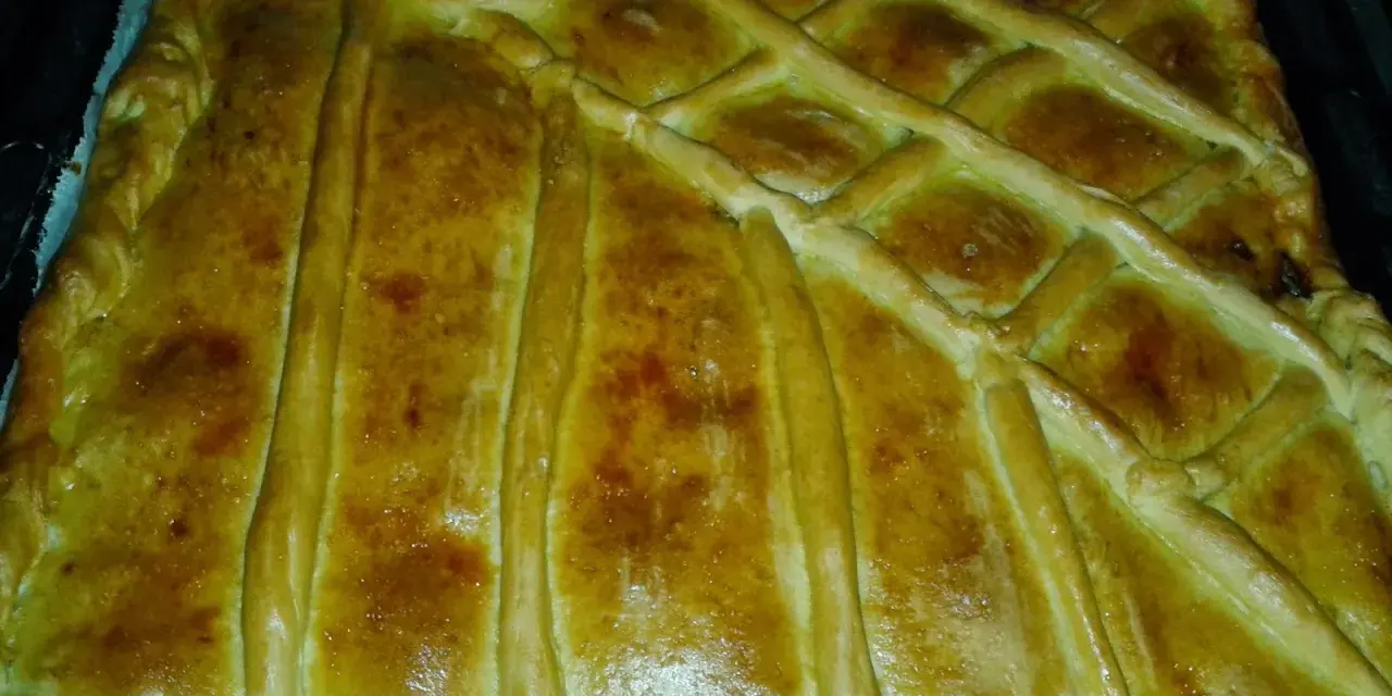 Empanada marinera dorada y crujiente, lista para disfrutar. Su masa cubierta con un enrejado perfecto promete un sabor delicioso.