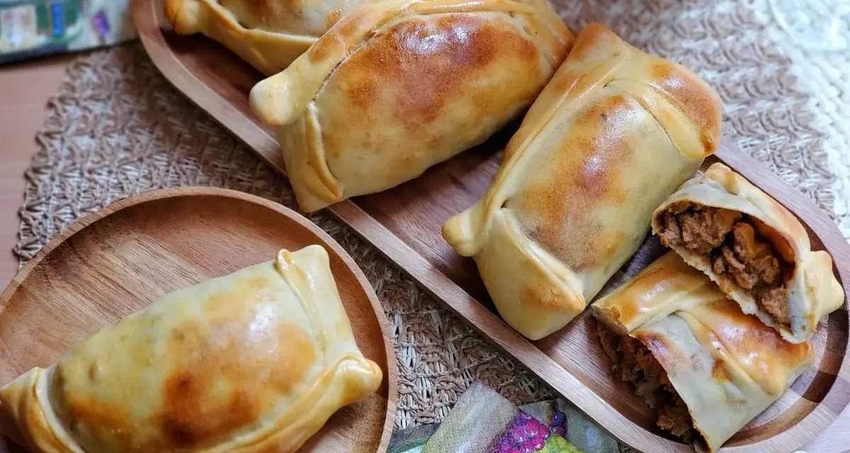 Deliciosas empanadas chilenas doradas, una rellena de carne cortada para mostrar su jugoso interior.