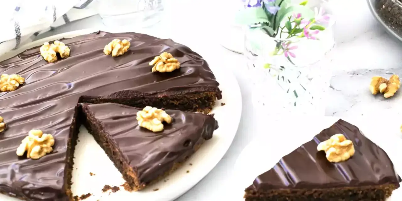 Delicioso pastel alemán de chocolate cubierto con glaseado brillante y nueces. Una rebanada ya servida.