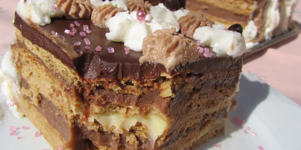 Delicioso postre Thermomix en capas de bizcocho y crema de chocolate, decorado con nata y granillo rosa.
