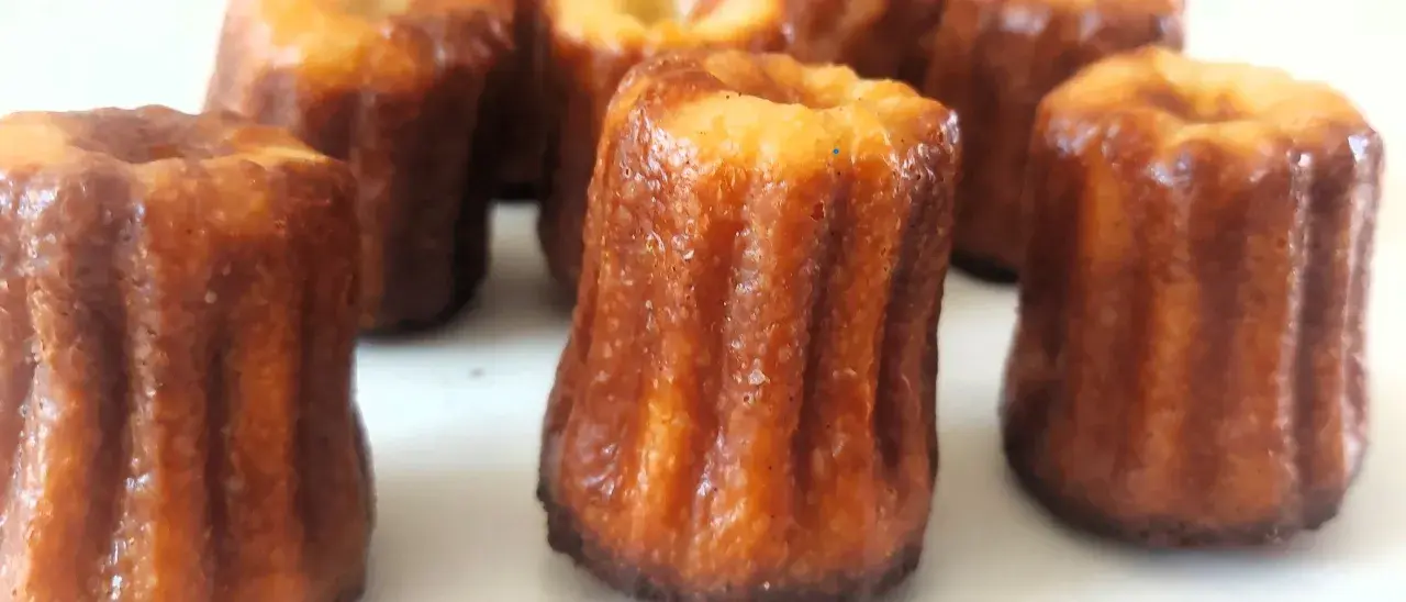 Un grupo de canelés de Bordeaux, con su característica corteza dorada y acanalada, listos para ser disfrutados.