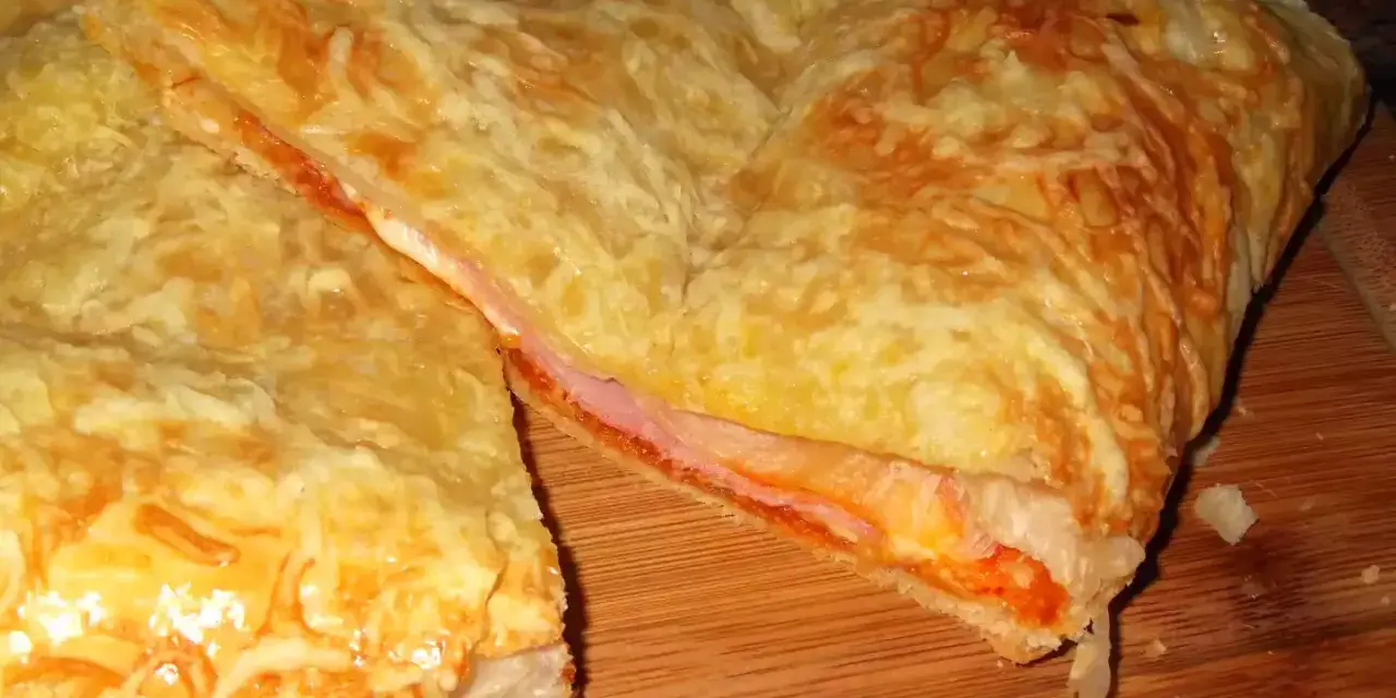 Empanada de jamón y queso dorada, con queso gratinado y relleno jugoso. ¡Un bocado delicioso!