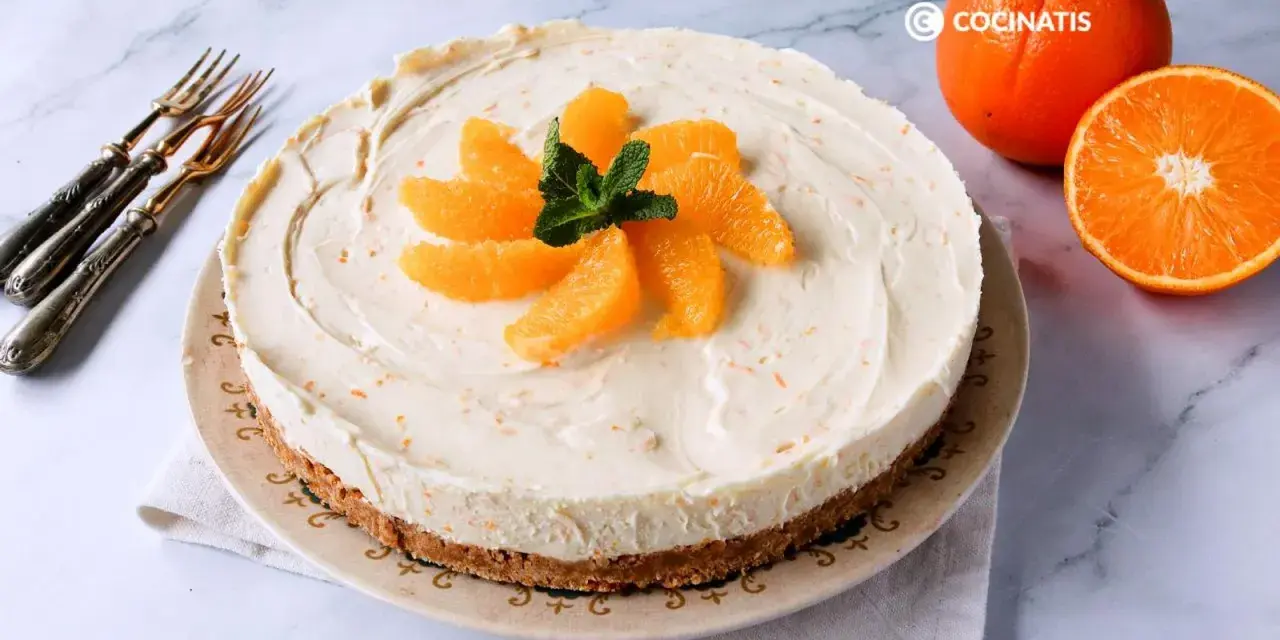 Tarta de naranja cremosa, decorada con gajos de naranja y menta. Perfecta para disfrutar de un postre refrescante.