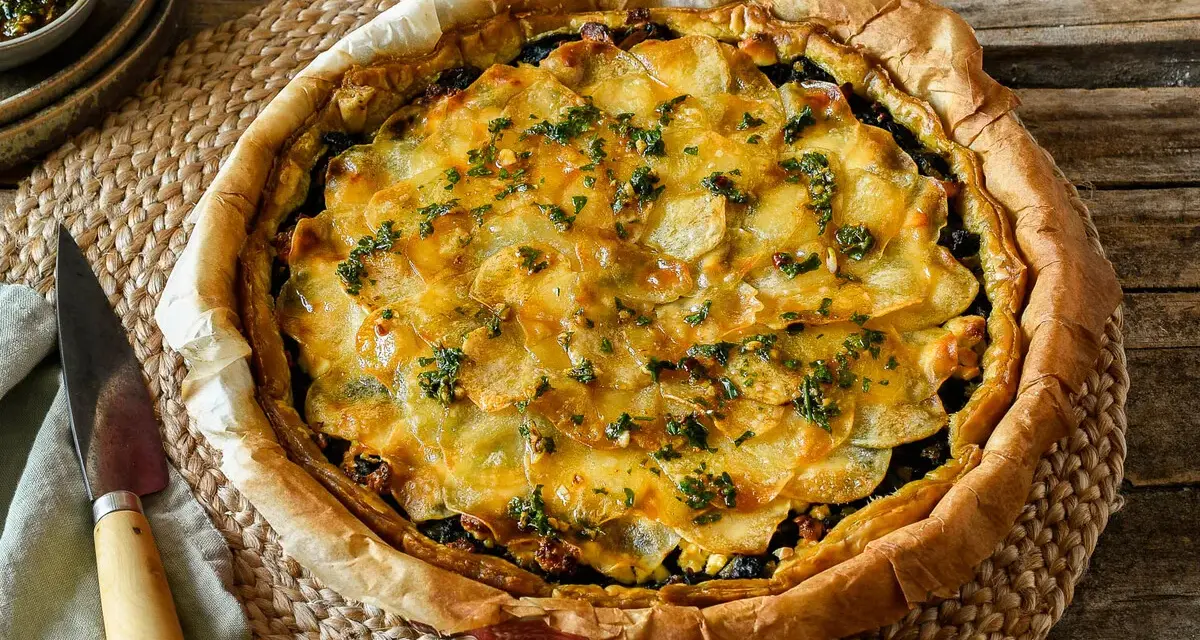 Delicioso quiche de espinacas con patatas laminadas y hierbas frescas, listo para servir.