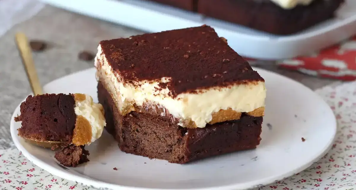 Un trozo de brownie de chocolate con una capa cremosa y espolvoreado de cacao. ¡Un delicioso brownie chocolate blanco!