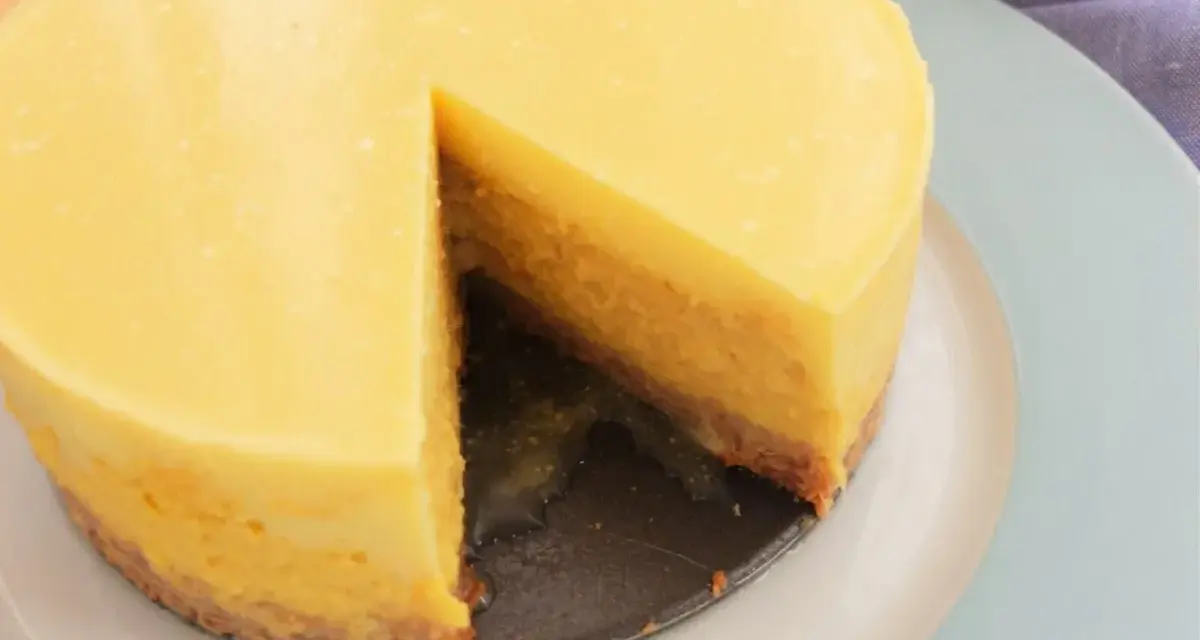 Tarta mango cremosa, con una porción retirada, sobre plato azul claro.