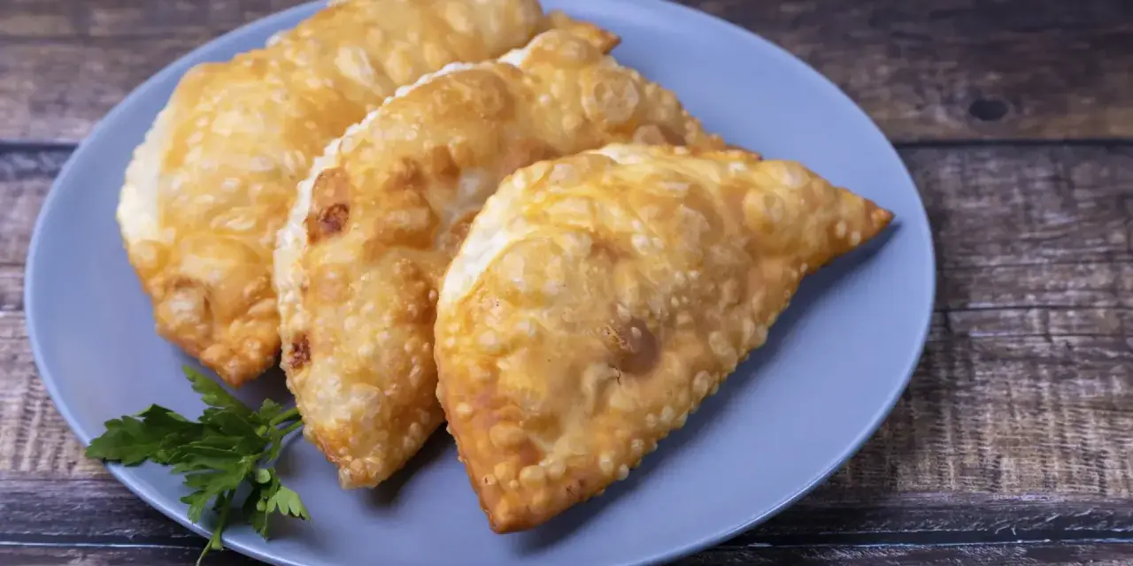 Tres empanadas doradas y crujientes, perfectas para tus recetas con obleas de empanadillas. Decoradas con perejil fresco.