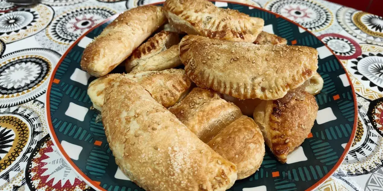 Plato lleno de empanadillas de cabello de ángel, doradas y espolvoreadas con semillas de sésamo.