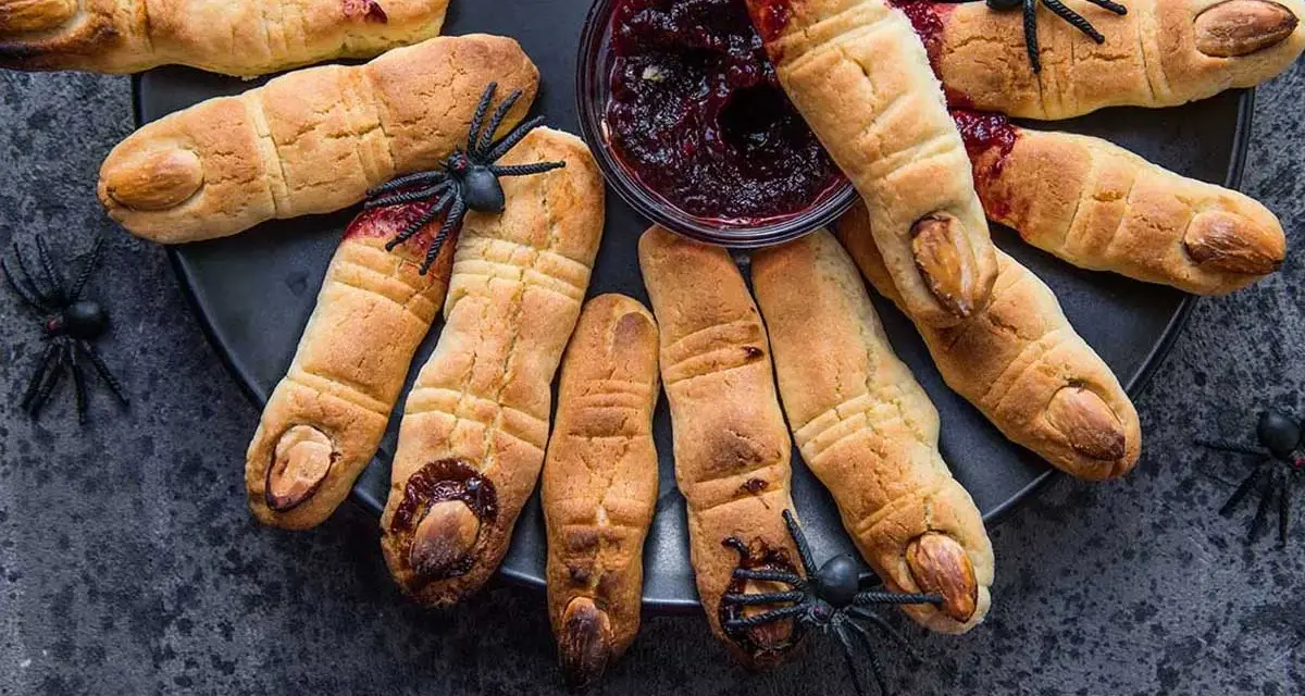 Galletas con forma de dedos, decoradas con almendras como uñas y mermelada roja simulando sangre. Un espeluznante postre de Halloween.